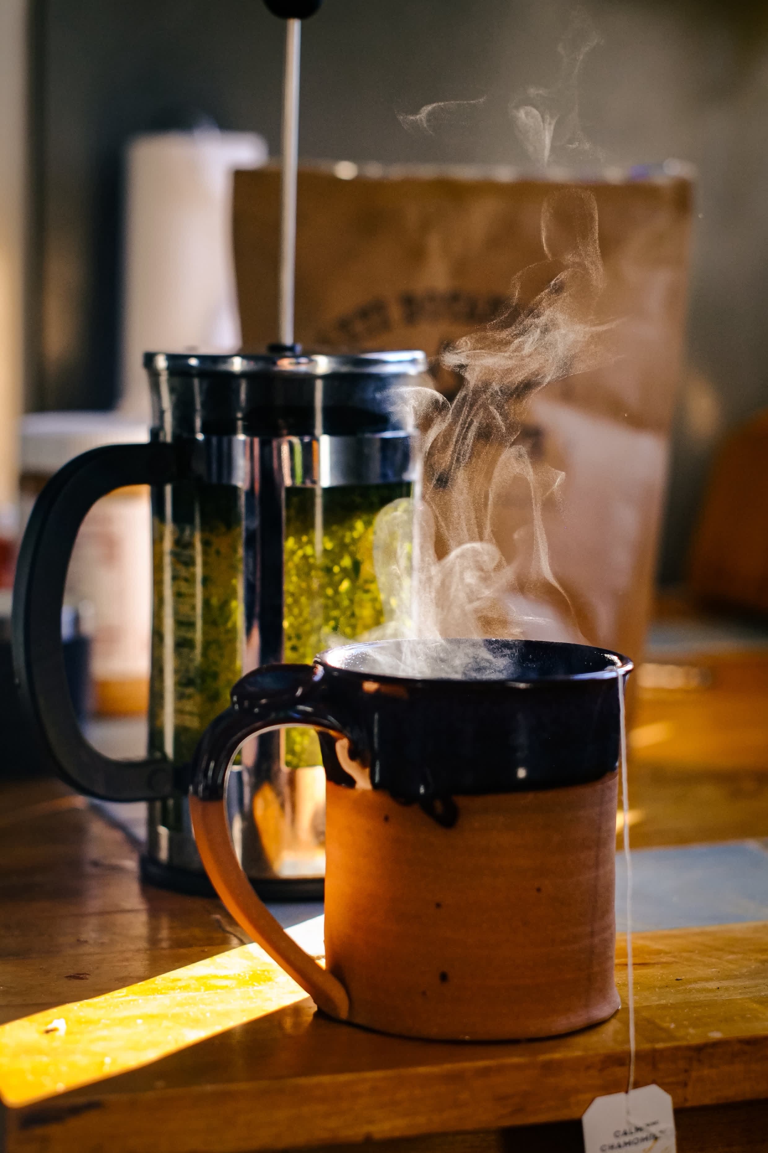Steaming mug beside a French press of Green Borneo crushed leaf tea